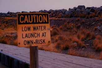 a yellow caution sign sitting on top of a wooden bridge