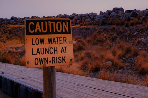 a yellow caution sign sitting on top of a wooden bridge