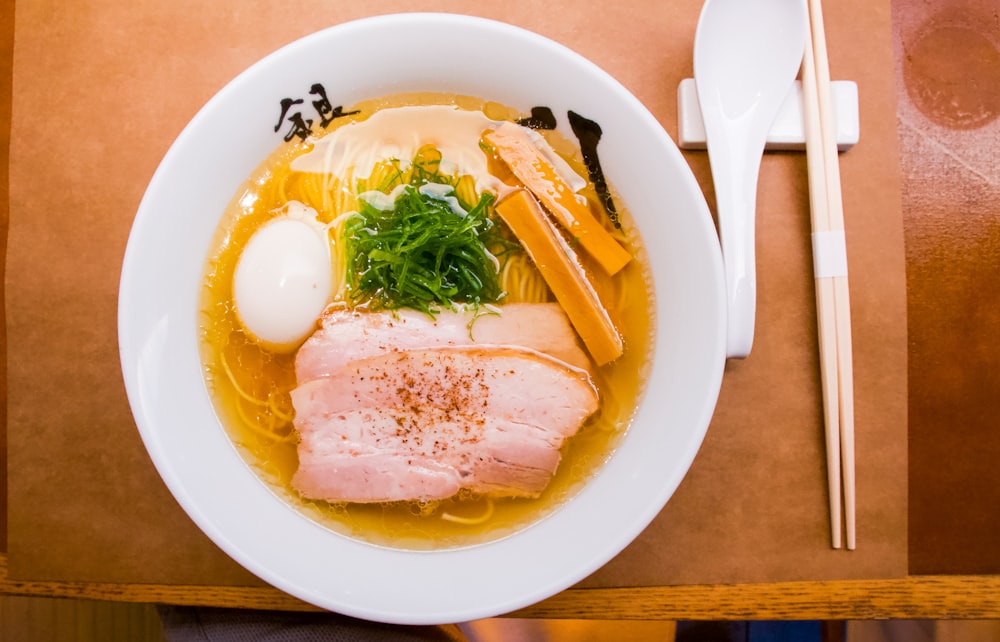 a bowl of soup with meat, vegetables and an egg