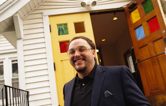 A welcoming real estate agent smiling while holding a set of house keys in a bright office.