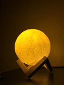 a yellow moon lamp sitting on top of a wooden stand