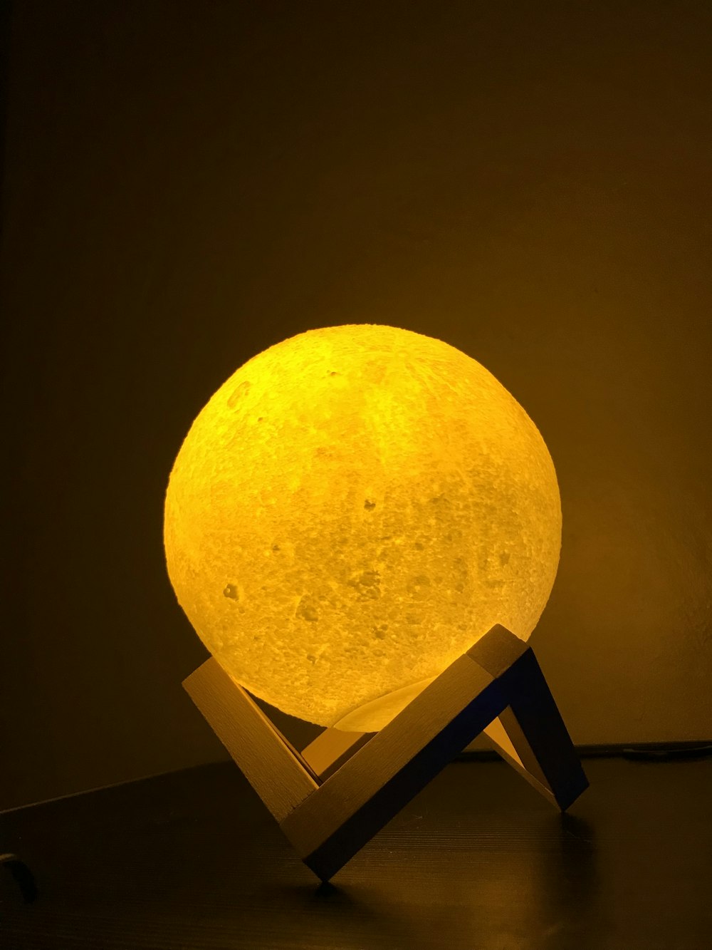 a yellow moon lamp sitting on top of a wooden stand