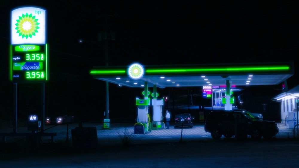 Una gasolinera iluminada por la noche con luces de neón