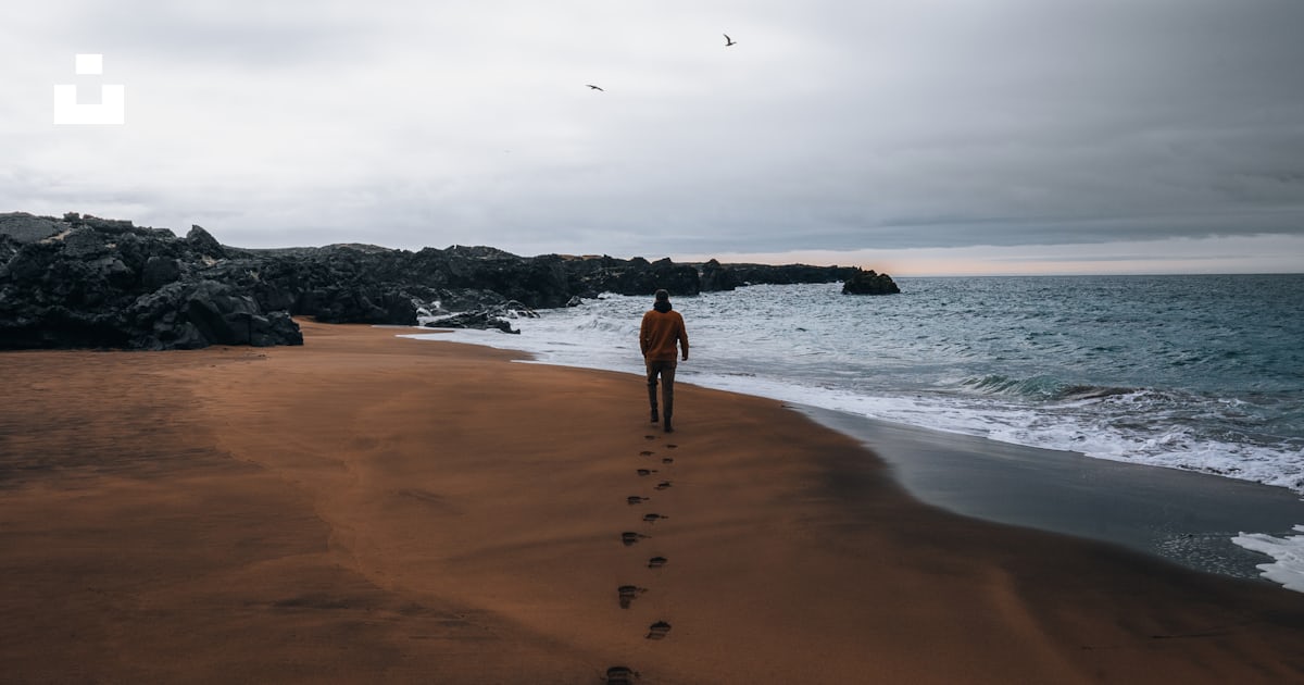 A person walking on a beach with footprints in the sand photo – Free ...