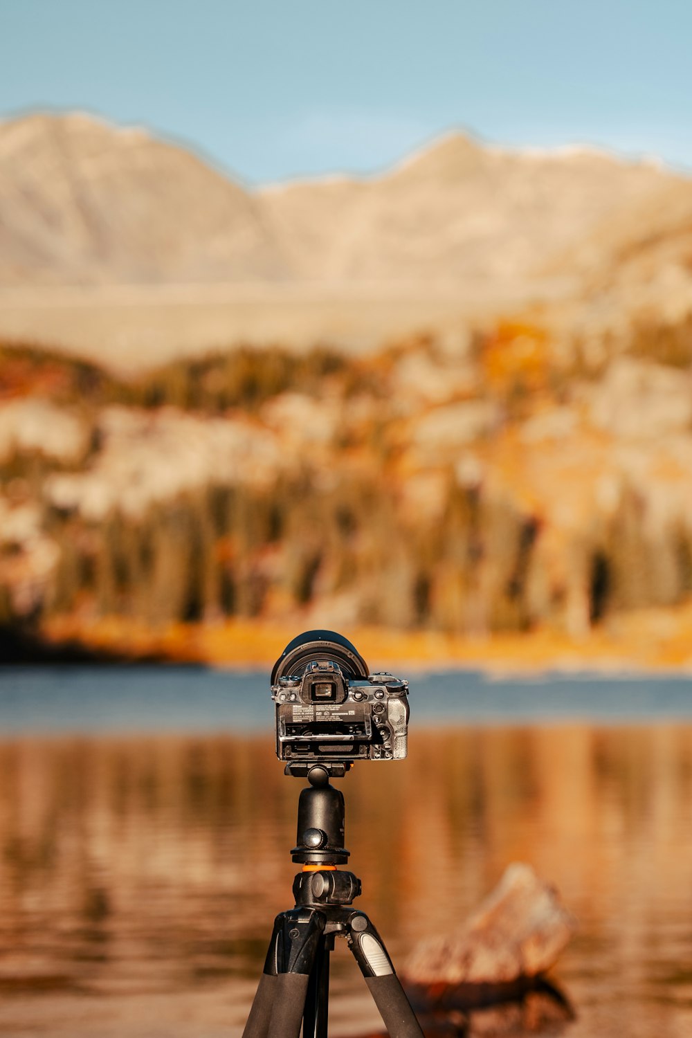 a tripod sitting on top of a lake next to a mountain