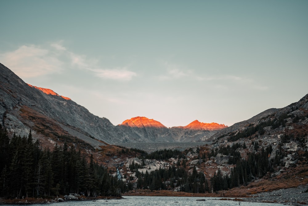 a lake surrounded by mountains with trees in the foreground