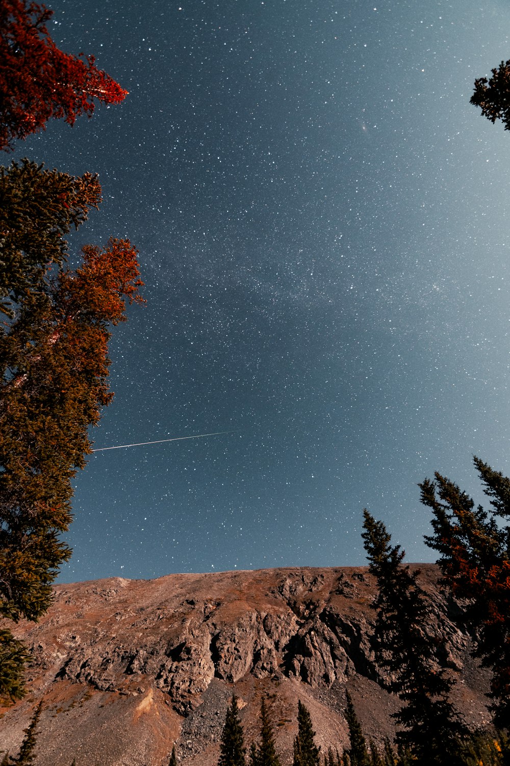 the night sky with stars above a mountain