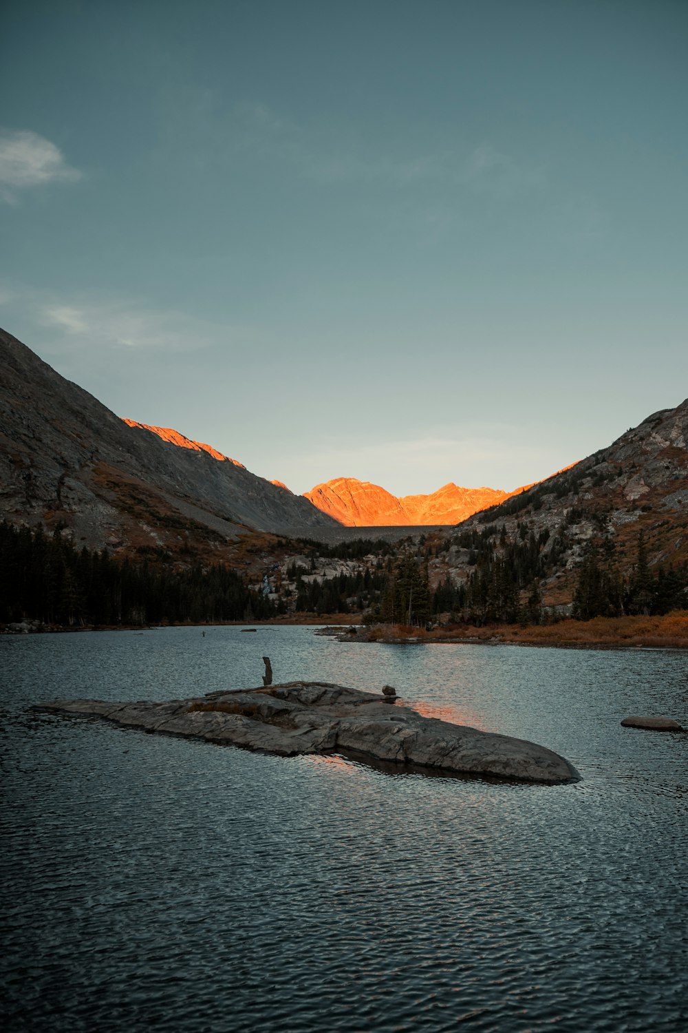 a person standing on a rock in the middle of a lake