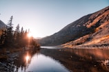 the sun shines on a mountain lake surrounded by pine trees