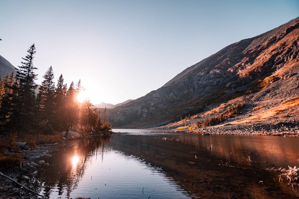 Le soleil brille sur un lac de montagne entouré de pins