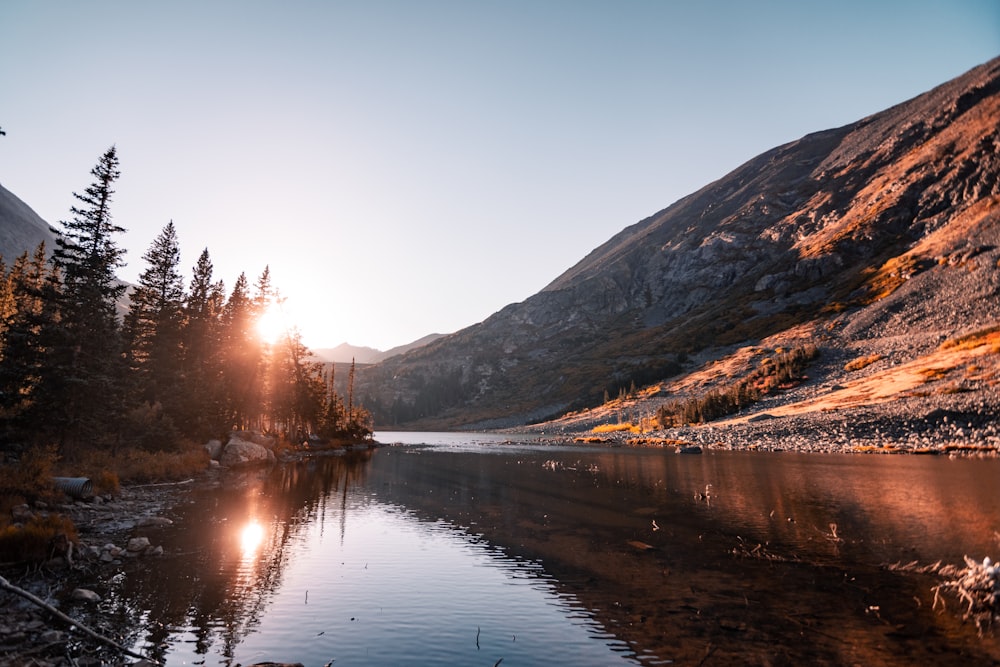 the sun shines on a mountain lake surrounded by pine trees