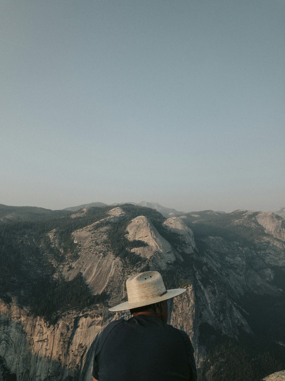 un uomo che indossa un cappello seduto sulla cima di una montagna