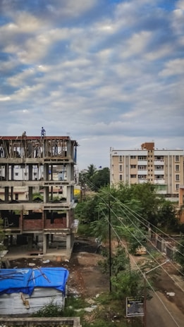 A construction site showing workers reviewing blueprints next to a partially built house.