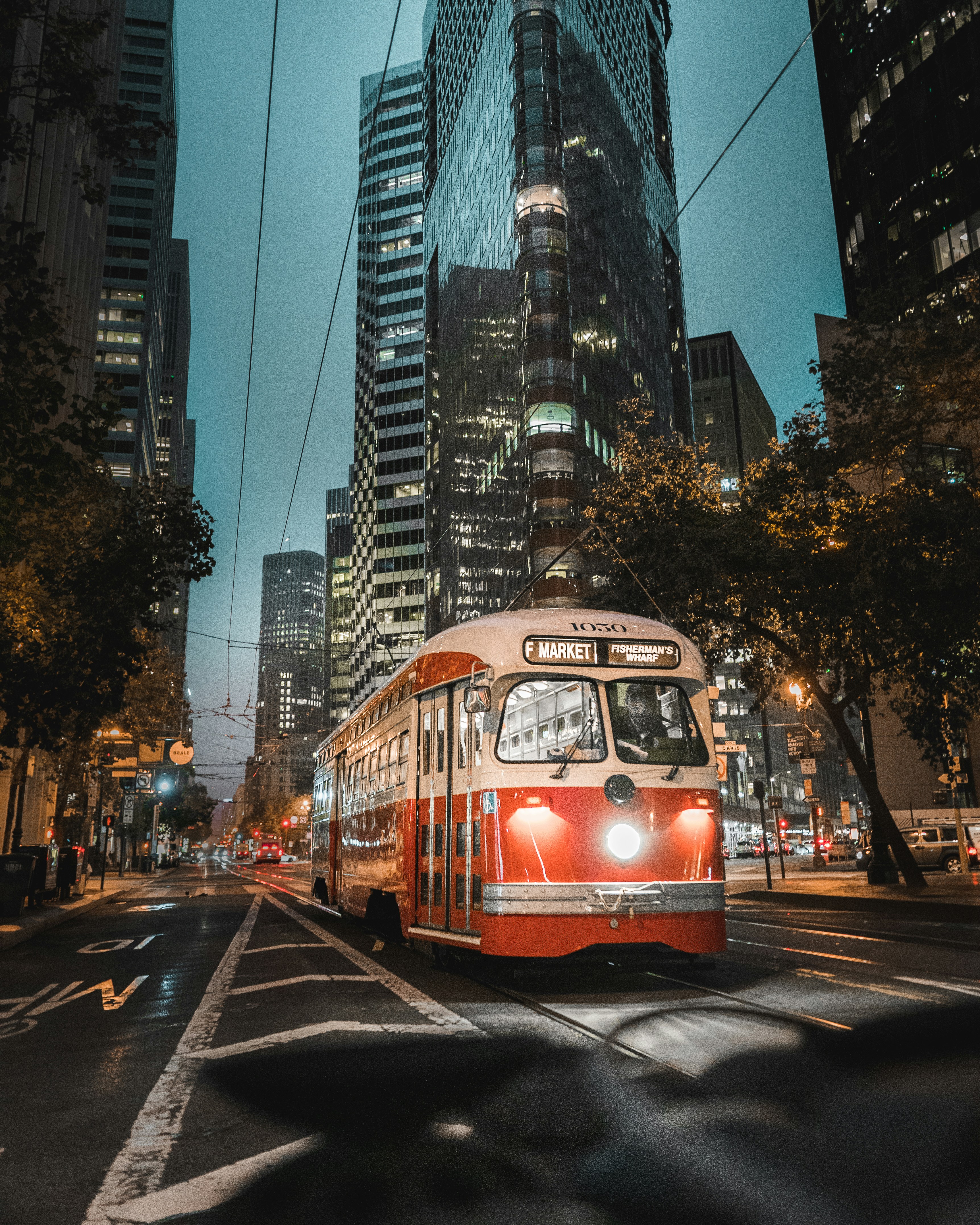a red and white bus driving down a street next to tall buildings
