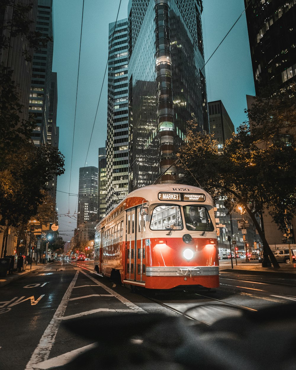 a red and white bus driving down a street next to tall buildings