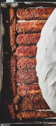 Close-up of a freshly made tiramisu with creamy layers and dusted cocoa powder on top.