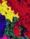 A vibrant mixture of colorful powdered pigments including red, yellow, green, blue, and pink, creating a textured and visually striking composition.