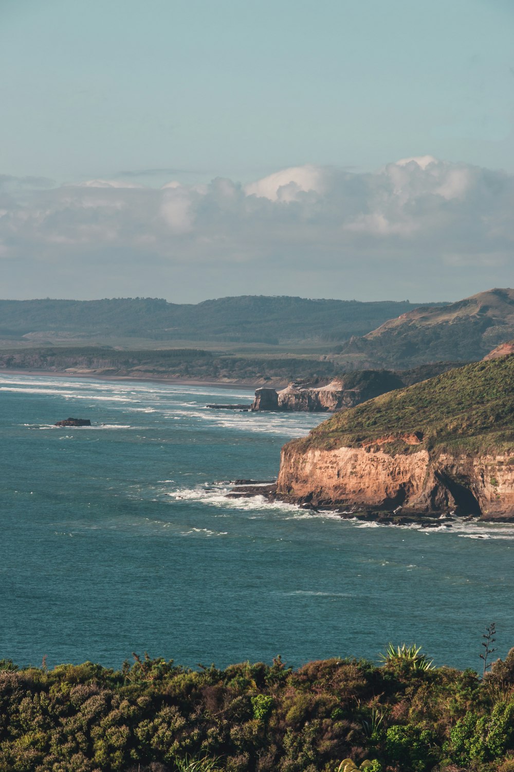 a large body of water sitting next to a lush green hillside