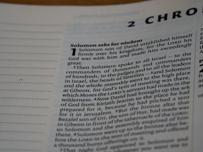 A close-up view of a text from a religious book, focusing on a chapter titled '2 Chronicles'. The passage 'Solomon asks for wisdom' is highlighted, and the text discusses Solomon's establishment over his kingdom and his request for wisdom from God. The page includes numbered sections and is written in a formal, structured format.