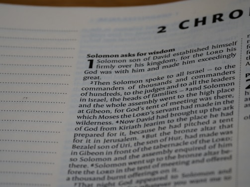 A close-up view of a text from a religious book, focusing on a chapter titled '2 Chronicles'. The passage 'Solomon asks for wisdom' is highlighted, and the text discusses Solomon's establishment over his kingdom and his request for wisdom from God. The page includes numbered sections and is written in a formal, structured format.