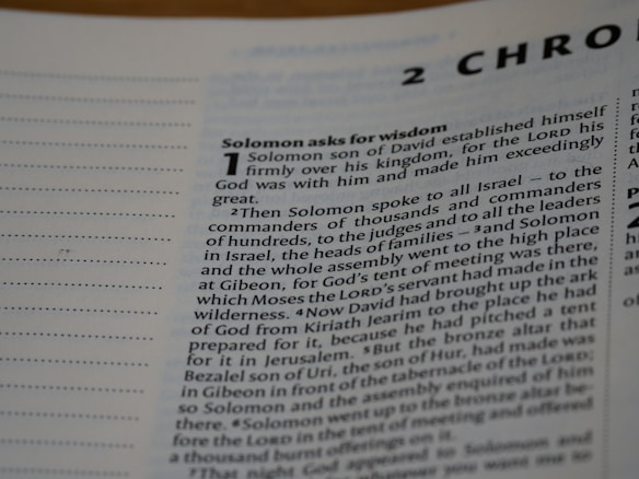 A close-up view of a text from a religious book, focusing on a chapter titled '2 Chronicles'. The passage 'Solomon asks for wisdom' is highlighted, and the text discusses Solomon's establishment over his kingdom and his request for wisdom from God. The page includes numbered sections and is written in a formal, structured format.