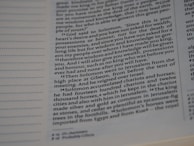 A close-up view of a page from a book displaying printed text. The text appears to be in English and contains paragraphs on the right side. There is a series of numbered verses in a column, likely from a religious or historical text, with some words emphasized in bold.