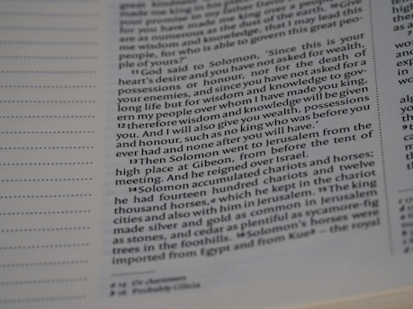 A close-up view of a page from a book displaying printed text. The text appears to be in English and contains paragraphs on the right side. There is a series of numbered verses in a column, likely from a religious or historical text, with some words emphasized in bold.