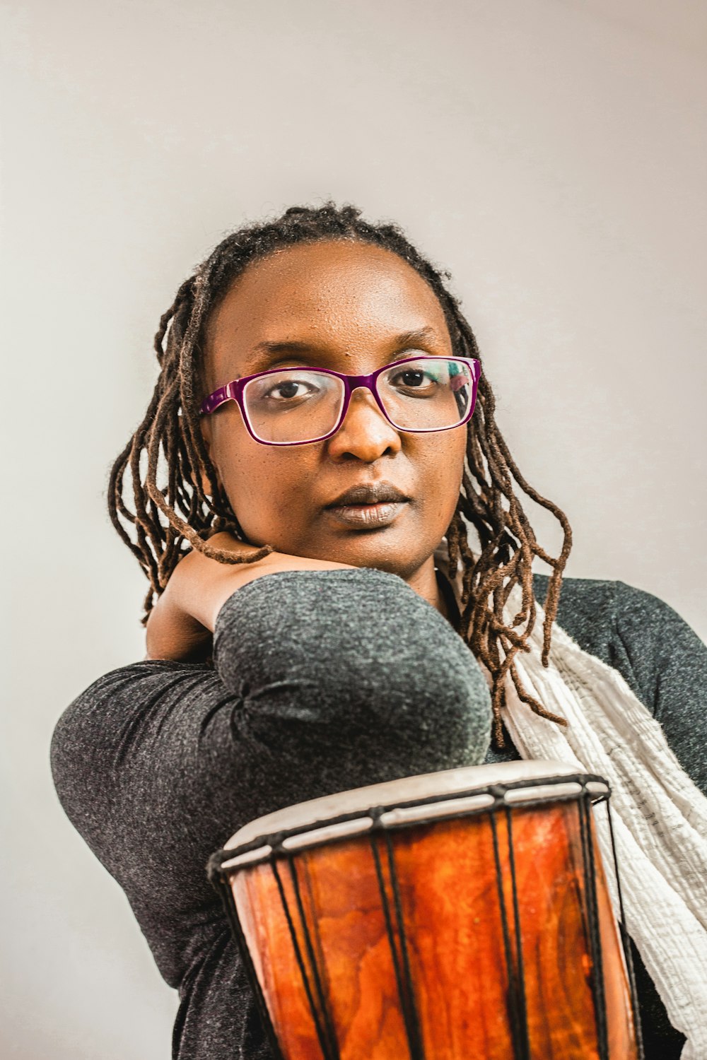 a woman with glasses is holding a drum