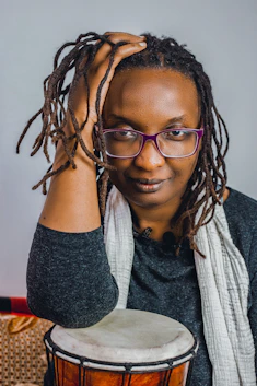a woman with glasses is holding a drum