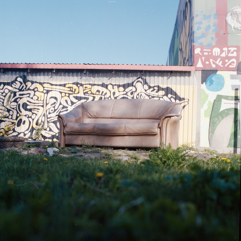 a couch sitting in front of a graffiti covered wall