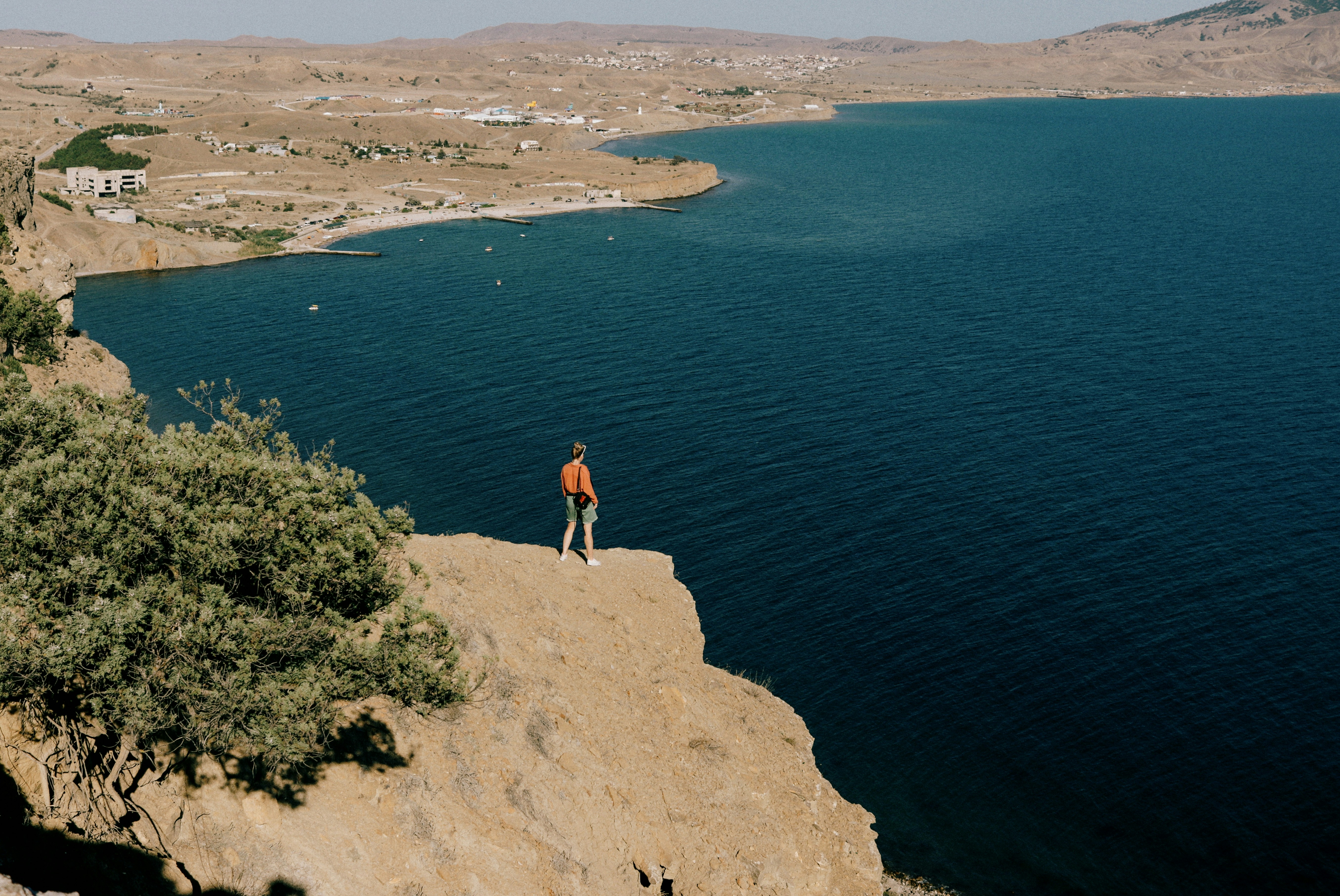 a man standing on top of a cliff next to a body of water
