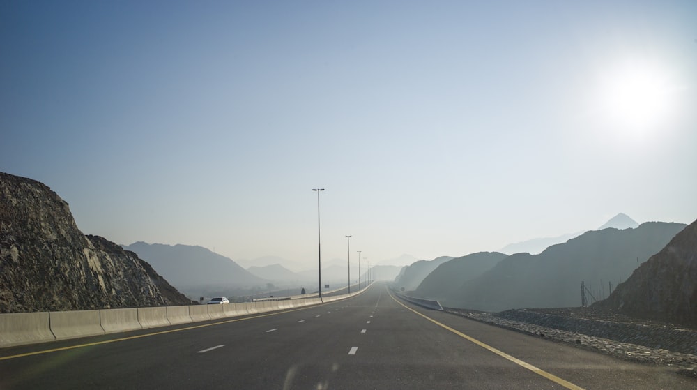 the sun shines brightly on a highway with mountains in the background
