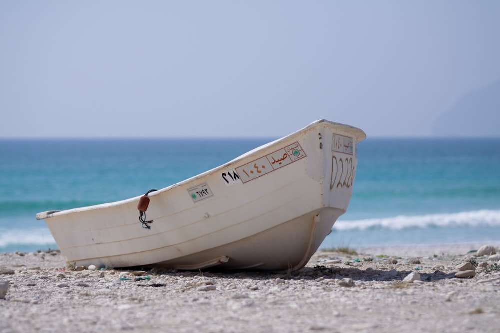 a white boat sitting on top of a sandy beach