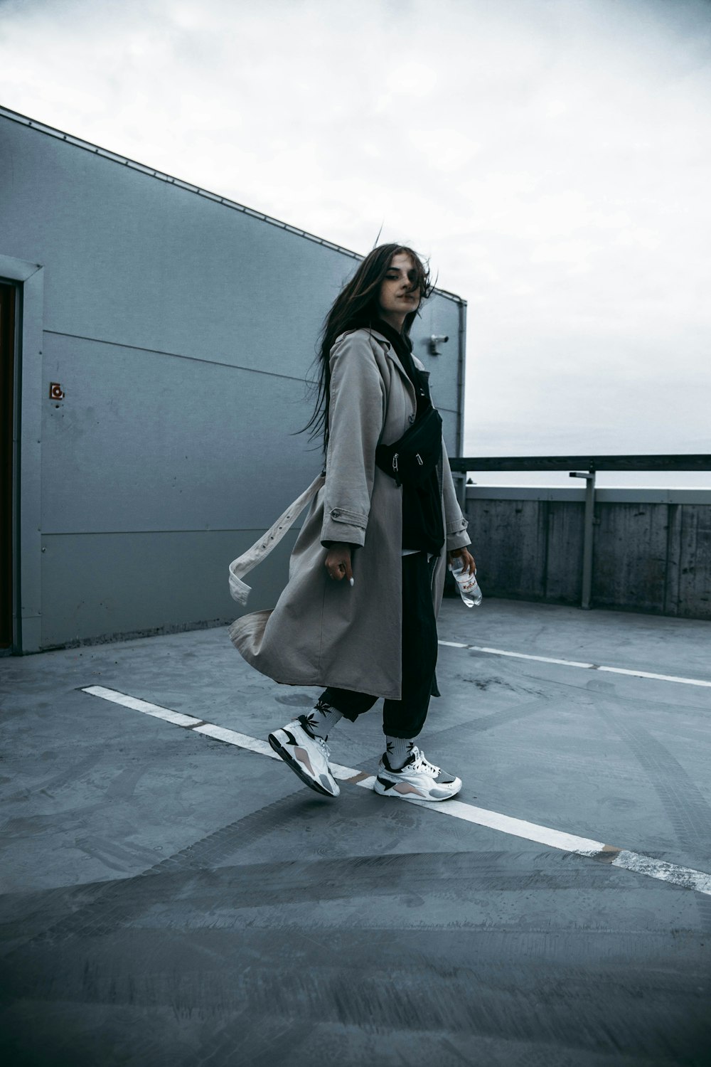 a woman walking across a parking lot wearing a coat