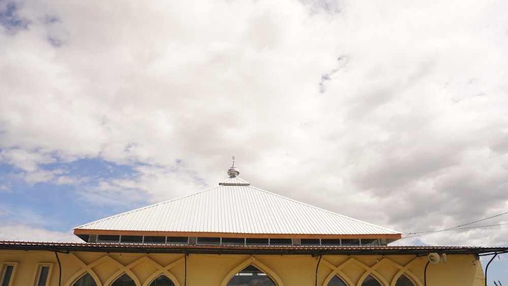 a yellow building with arched windows and a white roof