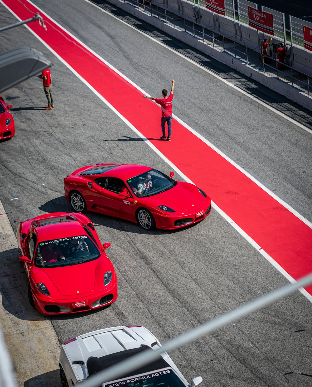 two red sports cars driving down a race track