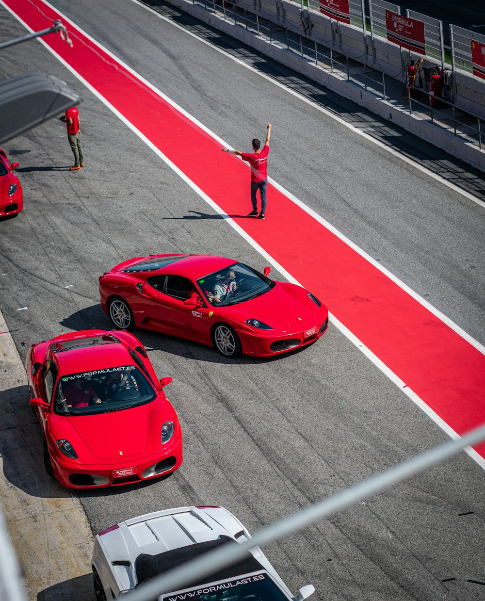 Dos autos deportivos rojos conduciendo por una pista de carreras