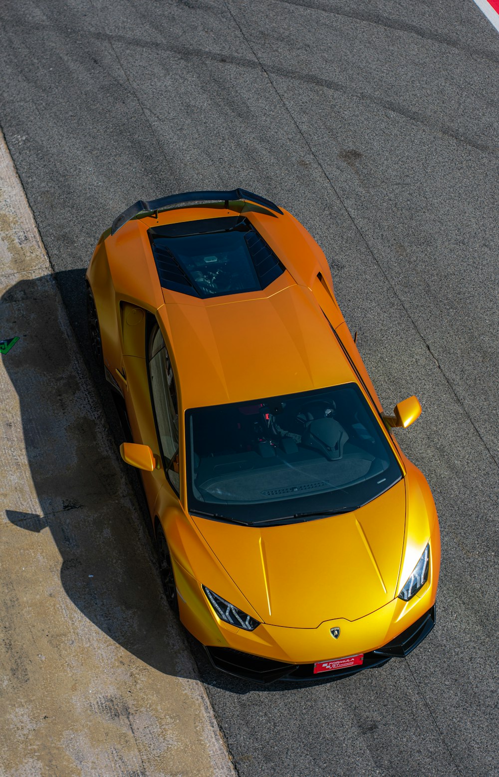 a yellow sports car driving down a race track