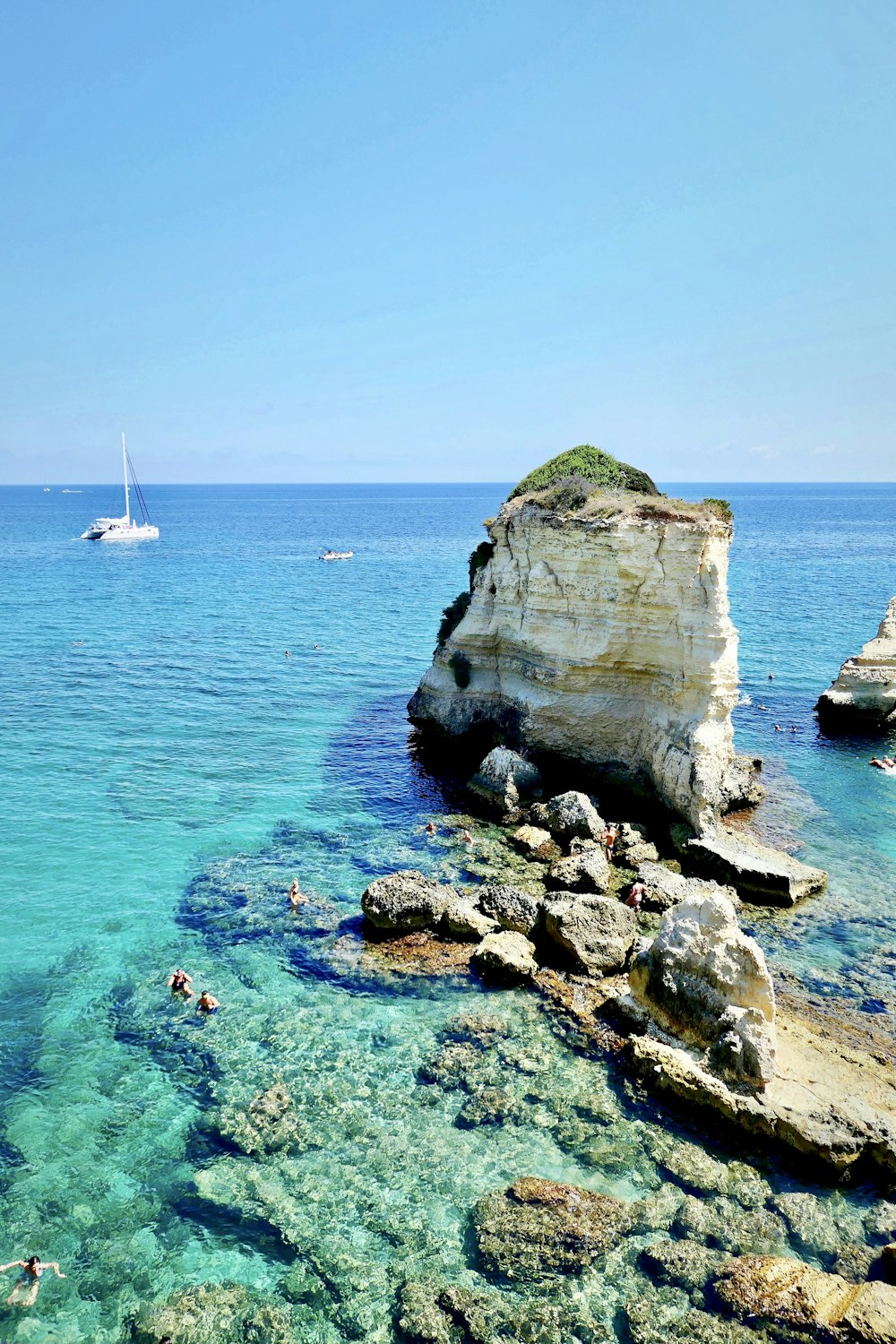 people swimming in the clear blue water of a beach