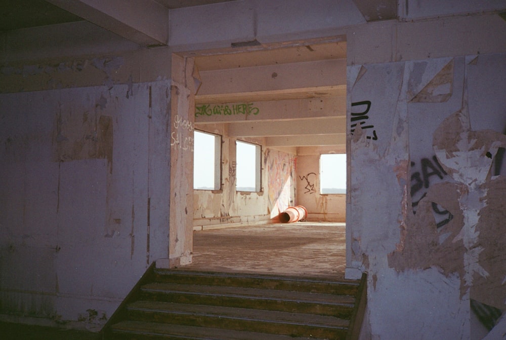 an empty room with stairs and graffiti on the walls