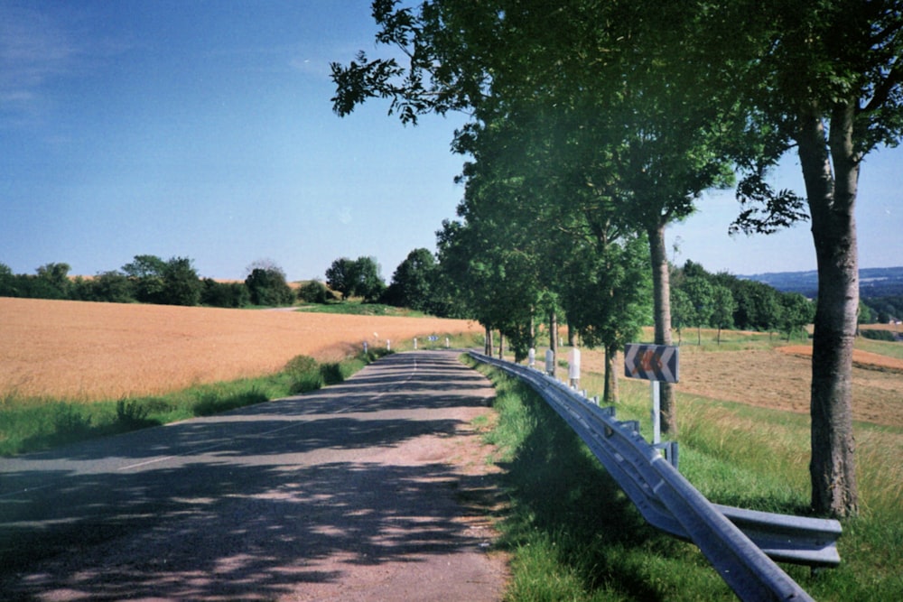 una strada di campagna con una recinzione e un campo sullo sfondo