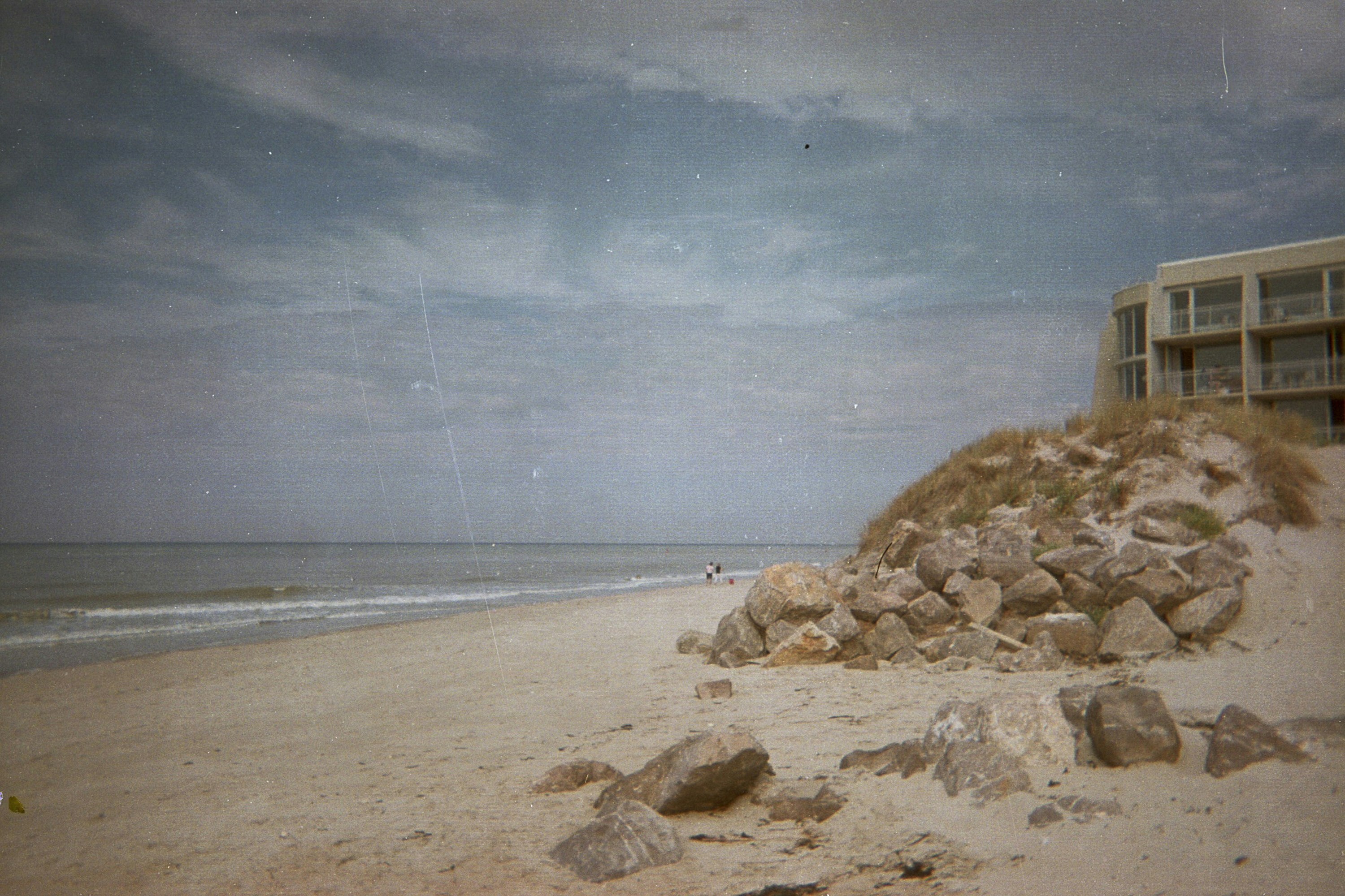 a sandy beach next to a building on a cloudy day