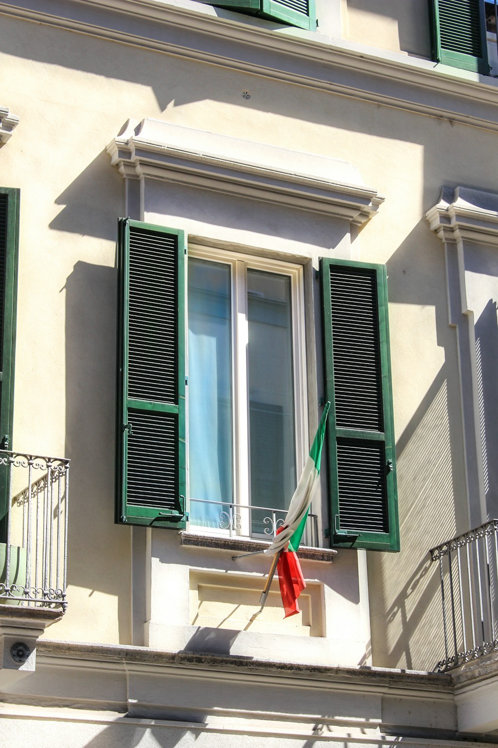 um edifício com persianas verdes e uma bandeira vermelha
