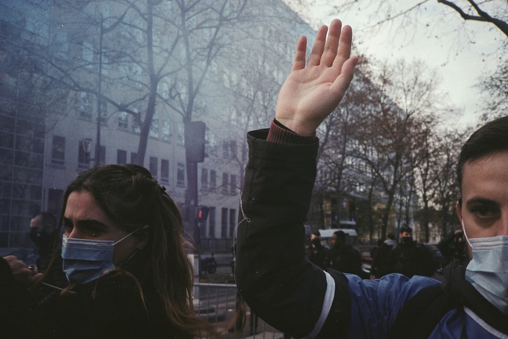 a man wearing a face mask waves to the crowd