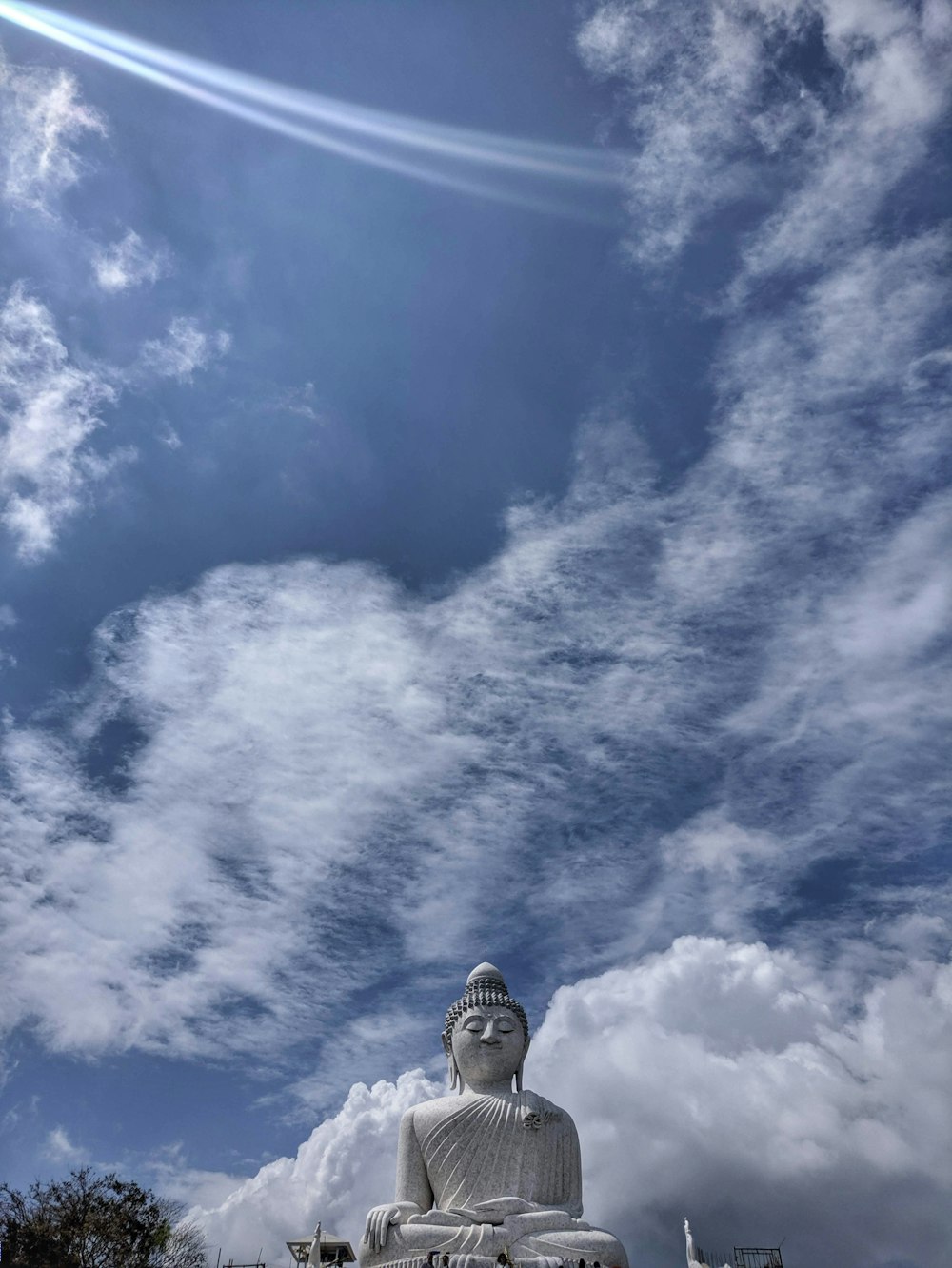 a large buddha statue sitting under a cloudy blue sky