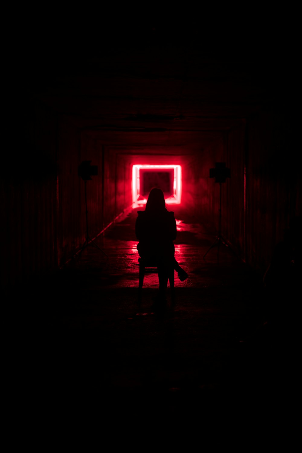 a person standing in a dark tunnel with a red light