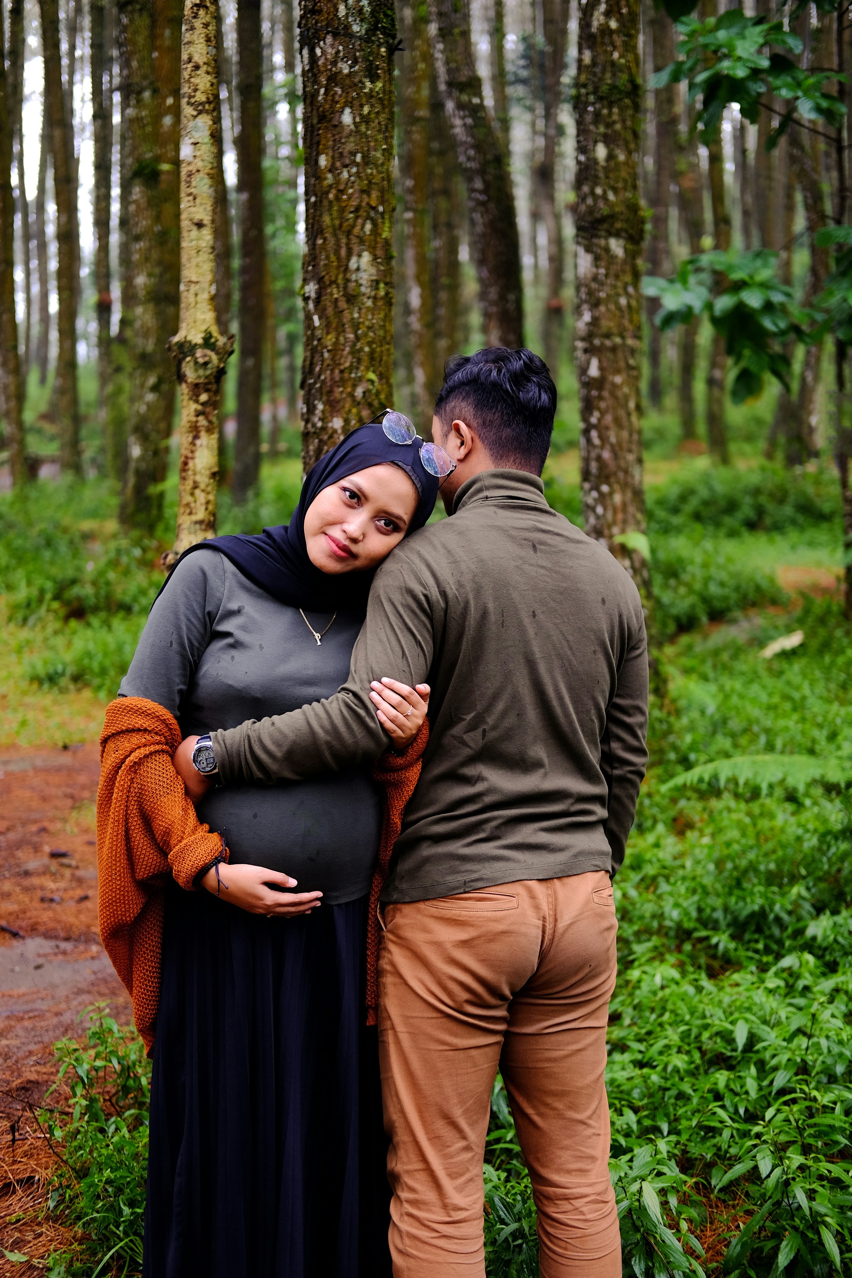 um homem e uma mulher de pé um ao lado do outro em uma floresta