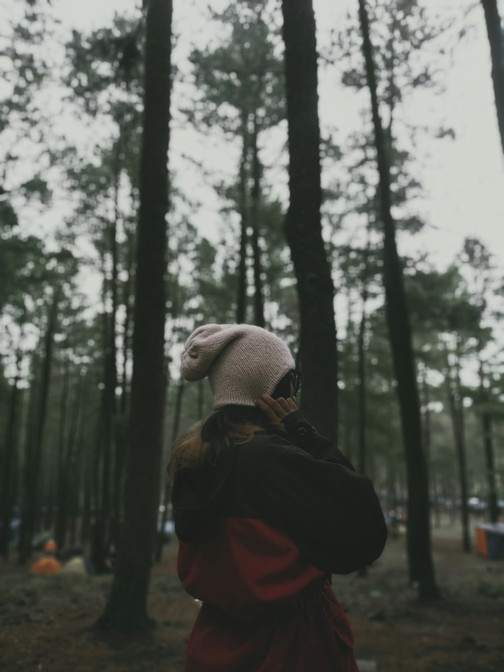 a person standing in the middle of a forest talking on a cell phone