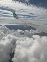 An airplane wing cutting through fluffy clouds, symbolizing affordable flights with Fly Deals.