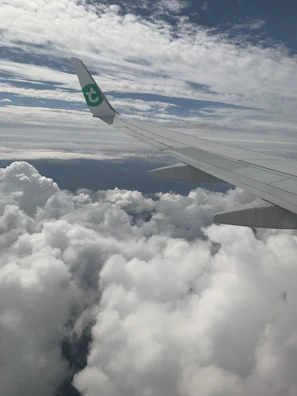 An airplane wing cutting through fluffy clouds, symbolizing the start of a new journey.